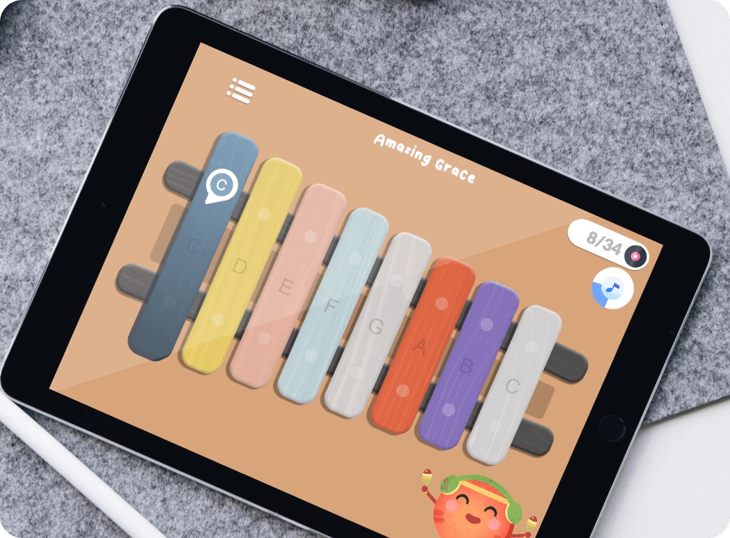 An iPad and apple pen on grey carpet with the display showing Xylophone Melodies colourful keys and its cute watermelon character holding shakers
